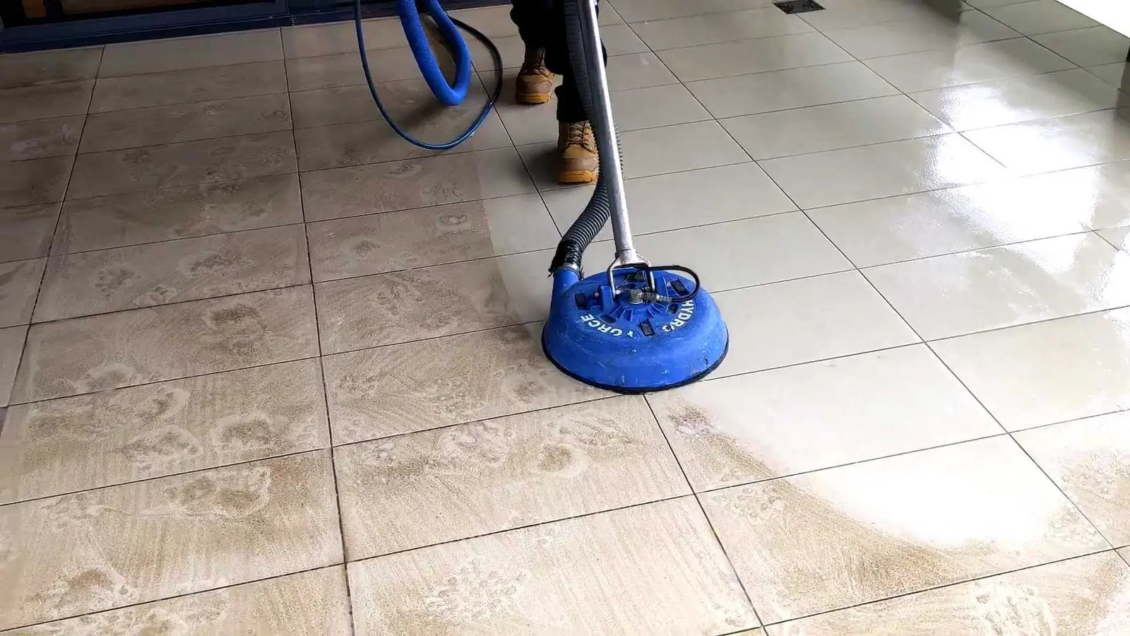 Tile and grout cleaning spinner between the soiled and freshly cleaned sections of a tiled floor